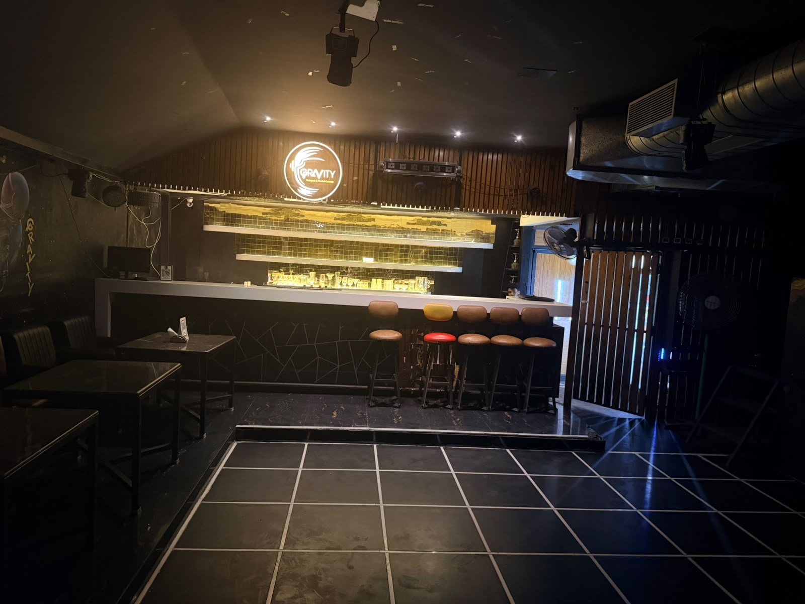 Warmly lit counter and high stools beneath the glowing Gravity sign